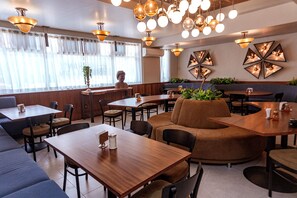 A restaurant interior with wooden tables, cushioned seating, and decorative wall art. - Hotel Melanie Tepic (Tepic)