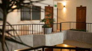 A hotel lobby with a concrete bench, a potted plant, and wooden doors. - Hotel Melanie Tepic (Tepic)