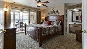 A bedroom with a large bed, a ceiling fan, a window, and a view of the outdoors. - Little House on the Fairway- Luxury Golf Condo (Branson)
