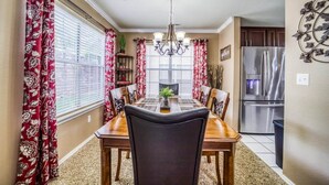 A dining room with a wooden table and chairs, a chandelier, and a refrigerator in the background. - Little House on the Fairway- Luxury Golf Condo (Branson)