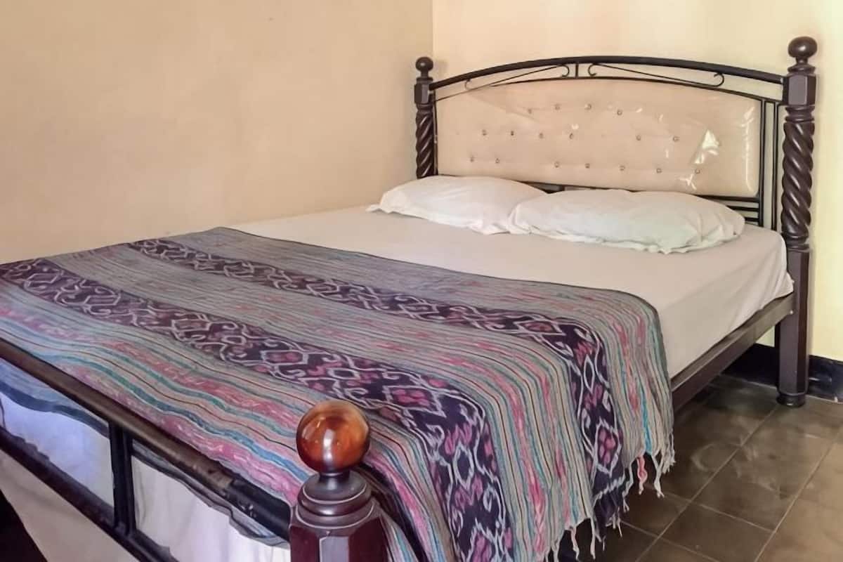 A bed with a patterned bedspread, a headboard, and a wooden headboard.