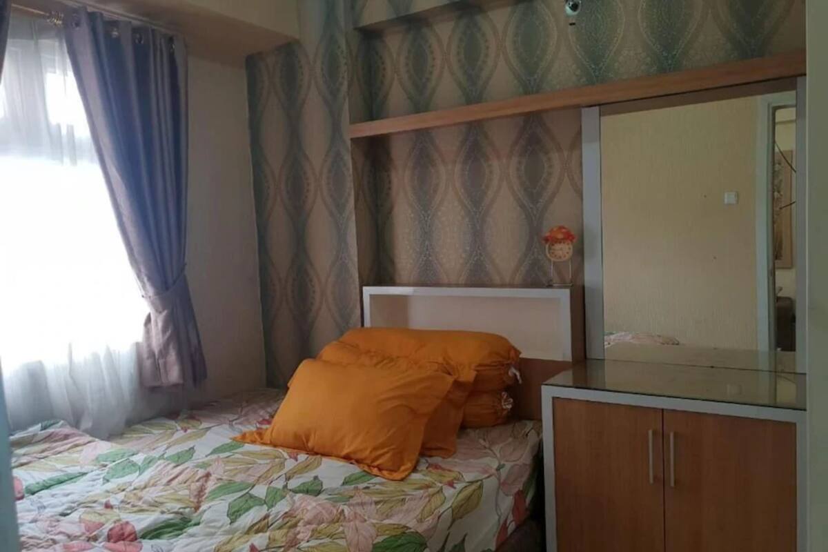Une chambre à coucher comprenant un lit, une table de chevet, un miroir et une armoire.