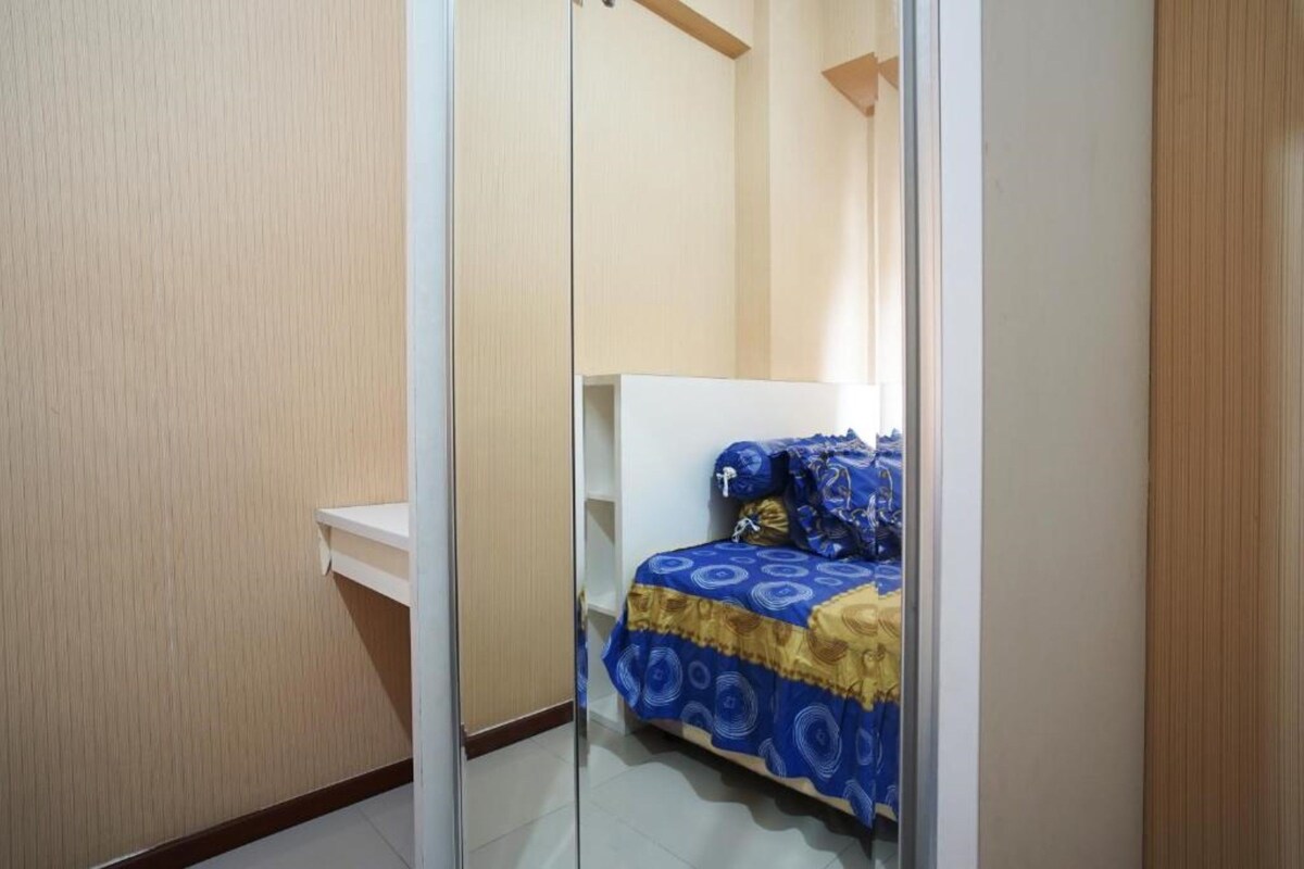A bedroom with a bed covered in a patterned bedspread, a bedside table, and a wardrobe.