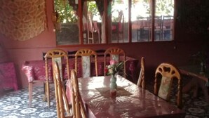 A dining area with a long table, chairs, and a patterned floor. - Merlyn Guest House (Samosir)