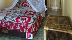 A room with a bed covered by a canopy, a bedside table, and a door with a curtain. - Merlyn Guest House (Samosir)