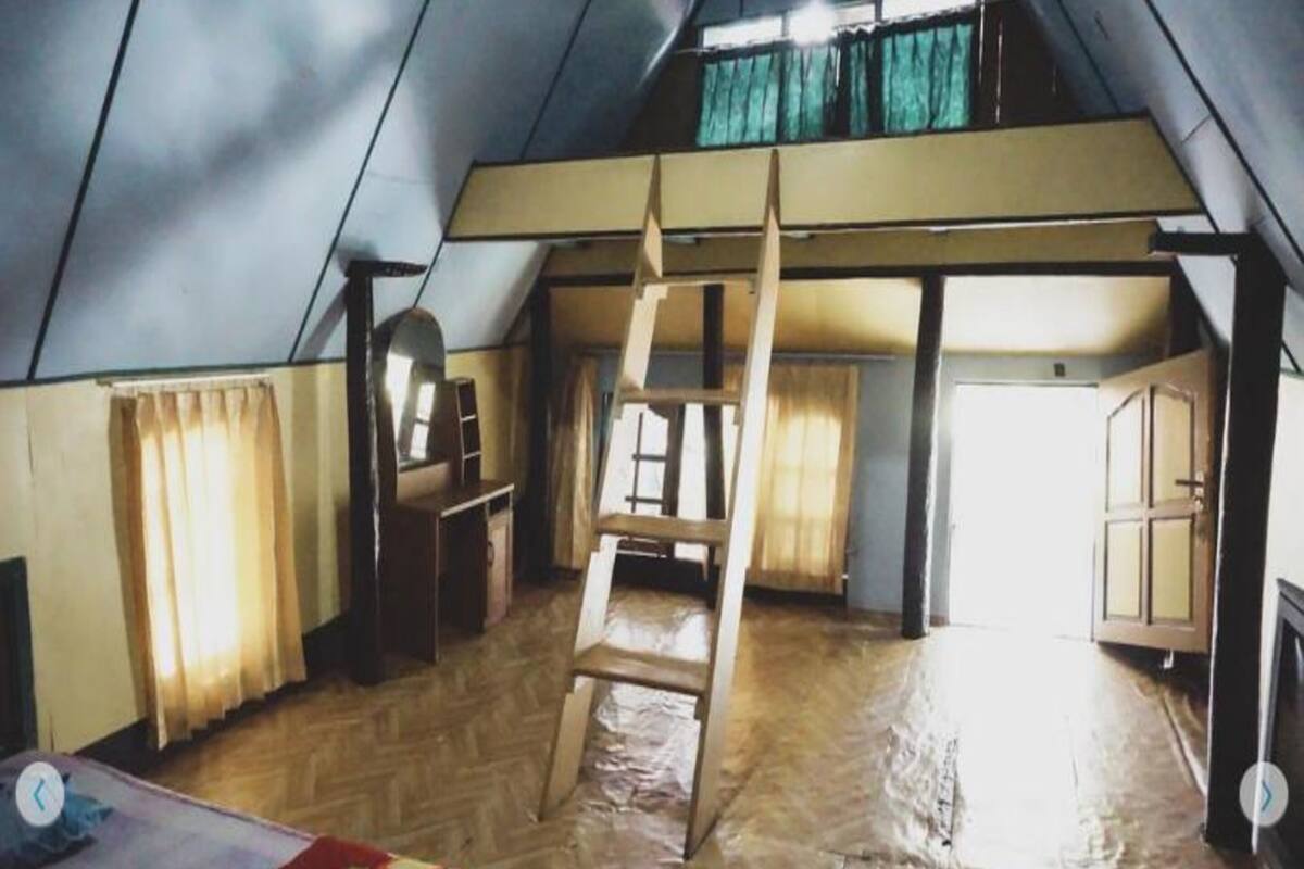 Una tienda de campaña con una escalera de madera, un escritorio y una silla.