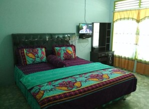 A bedroom with a bed, a television, and a window with curtains. - Marroan Guest House (Samosir)