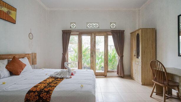 A hotel room with a bed, a wooden wardrobe, a desk, and a chair. - Karan Homestay Canggu (Canggu)
