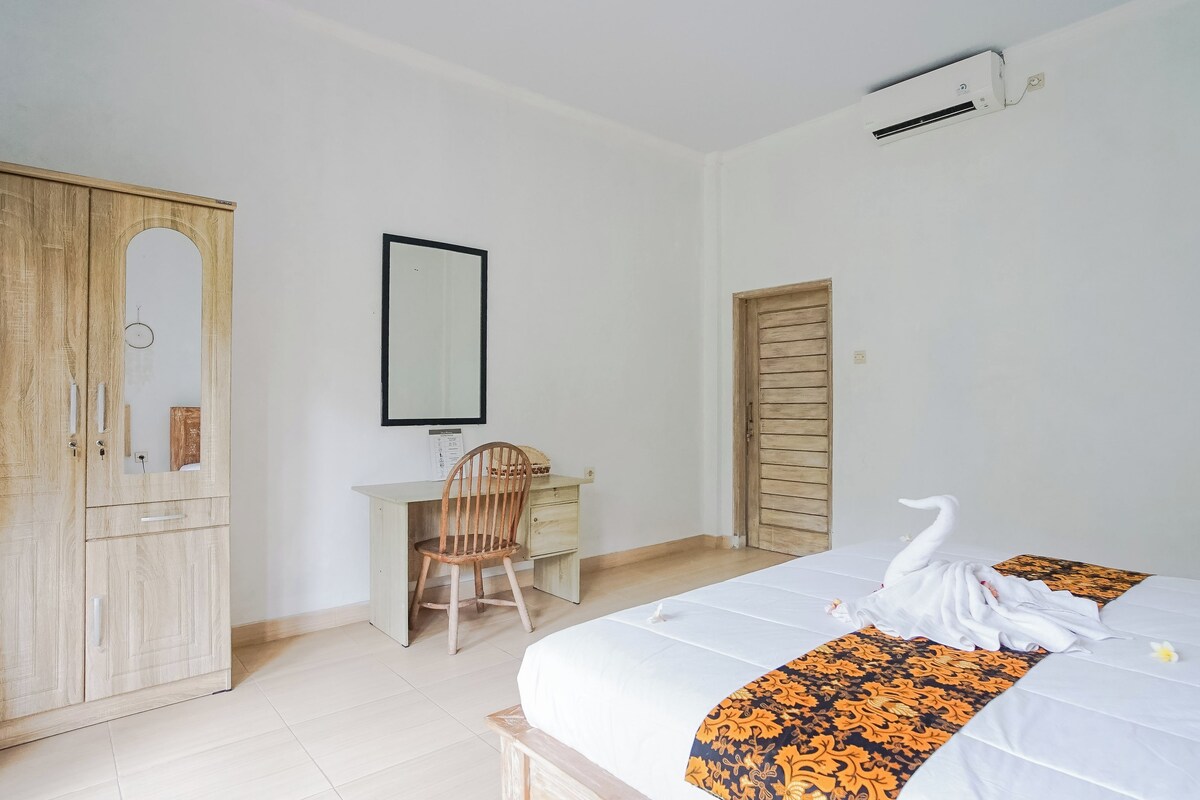 Ein Schlafzimmer mit Bett, Schreibtisch, Stuhl, Kleiderschrank und Spiegel.