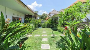 A garden pathway leading to a building with a tiled roof. - Karan Homestay Canggu (Canggu)