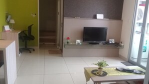 A living room with a television, a desk, a chair, a sofa, and a small table with a plant. - Luxury Living At The Edge (Cimahi)