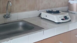 A kitchen with wooden cabinets, a stainless steel sink, and a white countertop. - Luxury Living At The Edge (Cimahi)