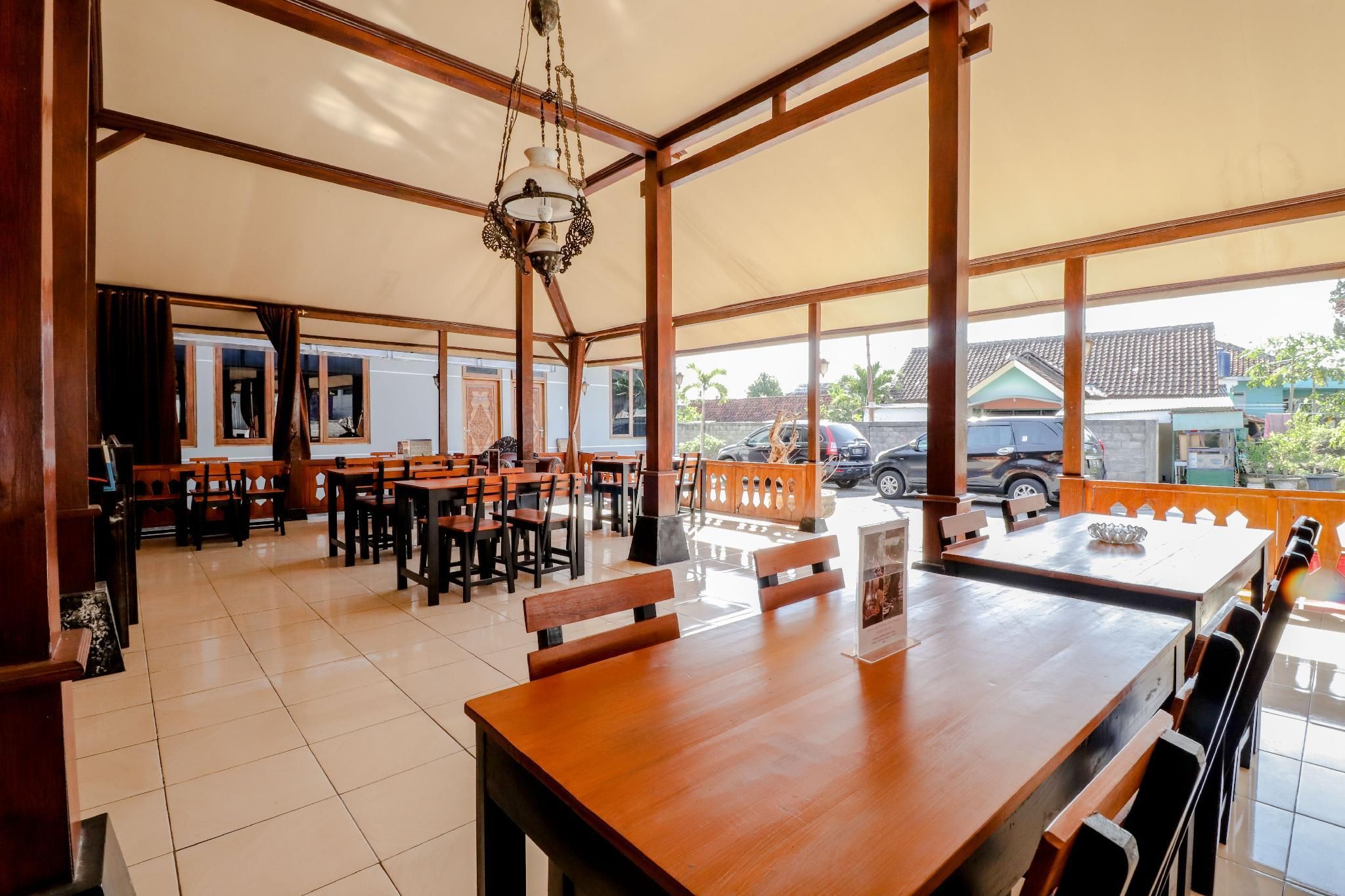 A spacious dining area with wooden tables and chairs, large windows, and a hanging light fixture.
