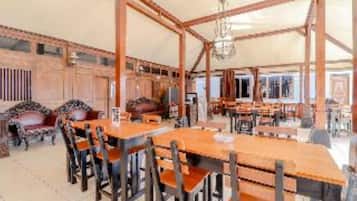 A spacious room with wooden tables and chairs, a chandelier, and a large window.