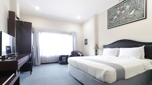 A hotel room with a bed, a television, a desk, and a chair. - Hotel Antariksa (Surabaya)