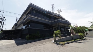 A multi-story building with a prominent 'HOTEL' sign, featuring a modern architectural design with balconies and a landscaped front area. - Hotel Antariksa (Surabaya)