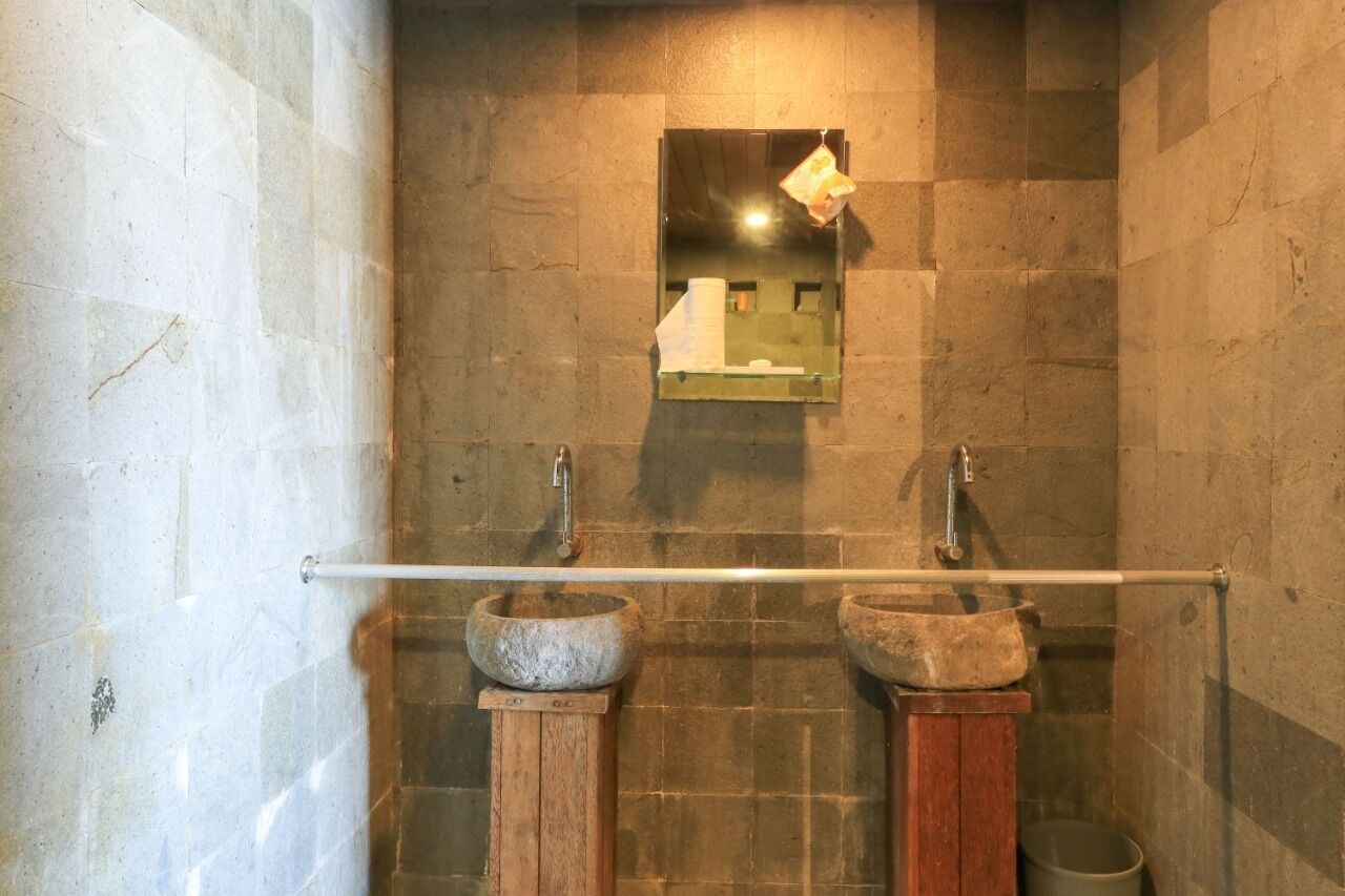 A bathroom with two stone sinks, a towel rack, and a mirror.