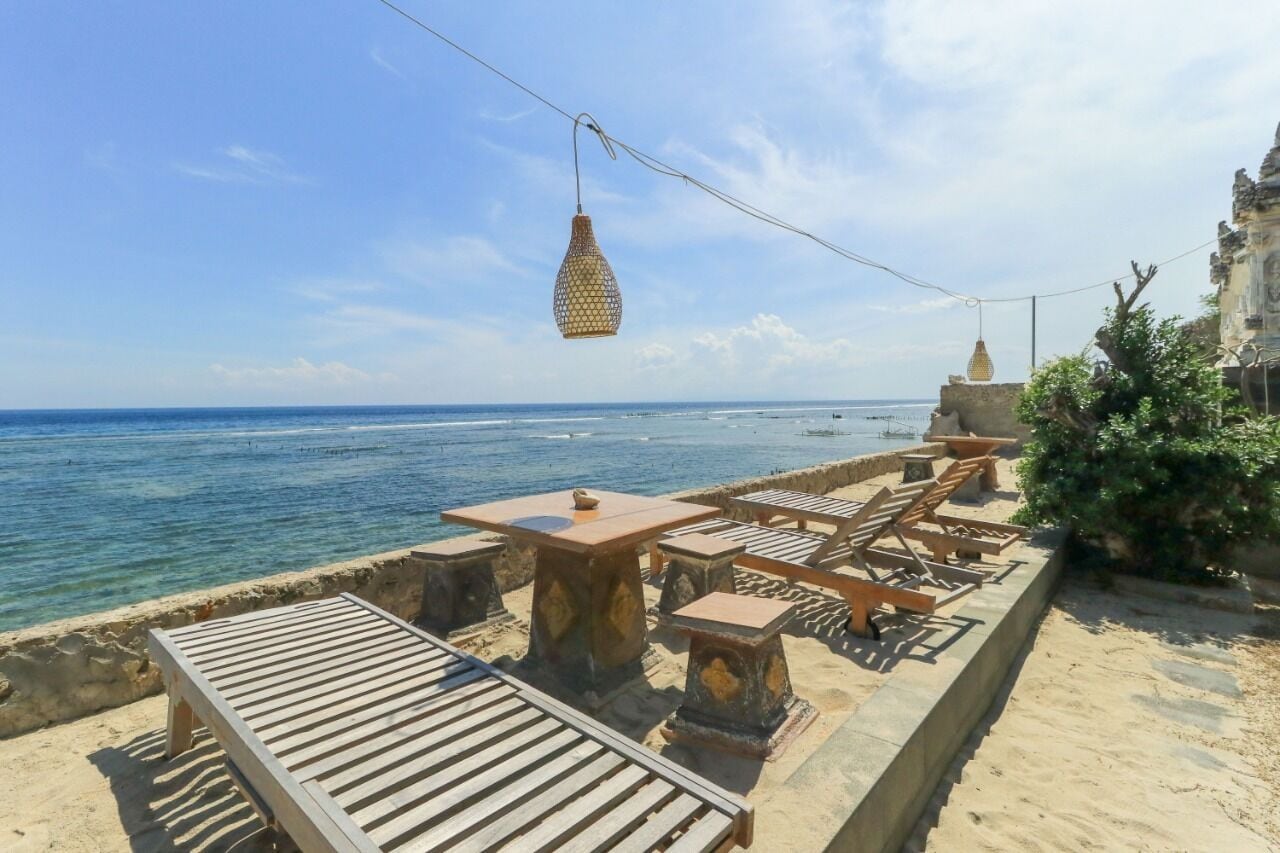 A seaside terrace with tables and chairs, overlooking the ocean.