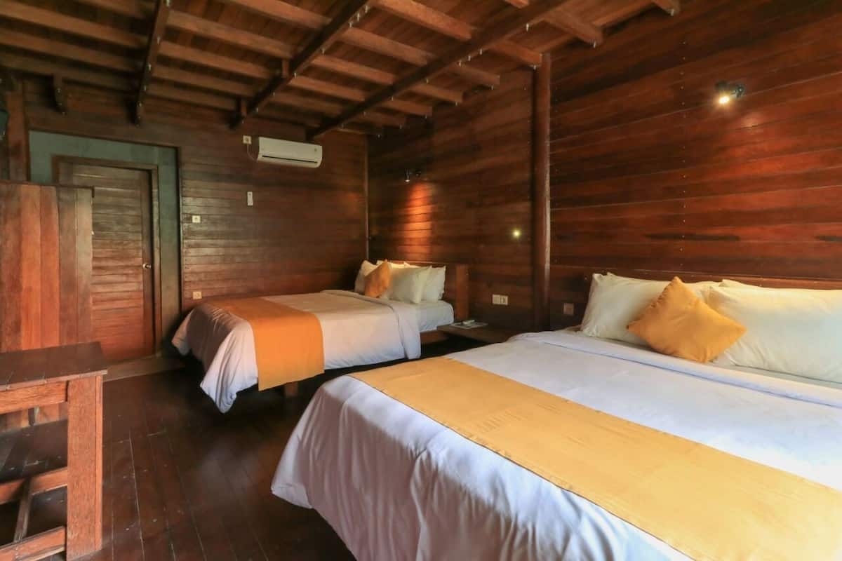 A wooden cabin room with two beds, a wooden desk, and a door.