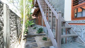 A staircase leading to a building with a traditional design, including a wooden handrail and decorative carvings.