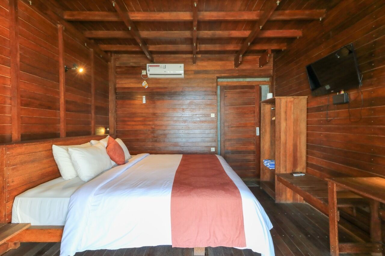 Una camera in una baita di legno con un letto, una televisione e un condizionatore d'aria.