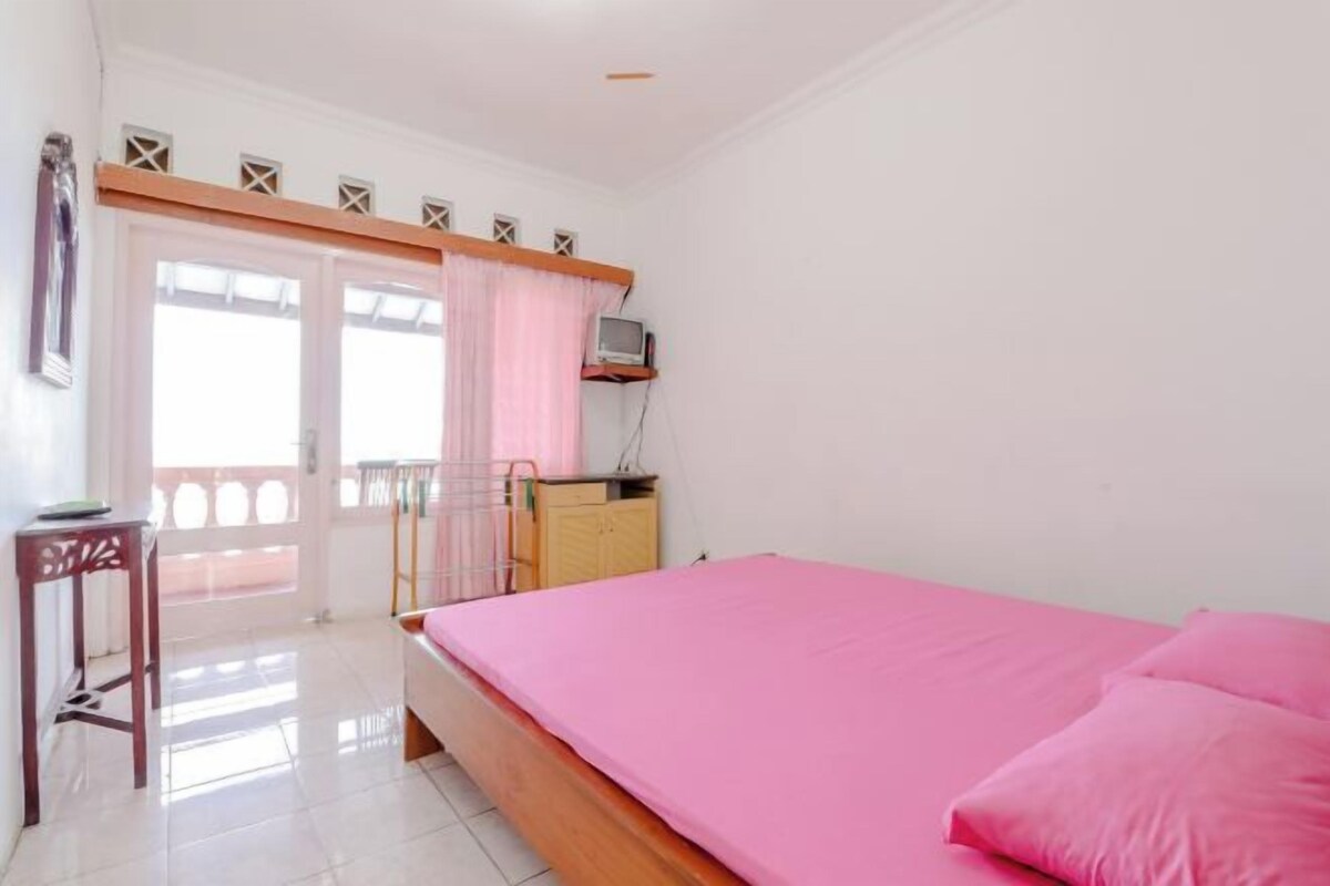 Ein Schlafzimmer mit Bett, Schreibtisch, Stuhl, Fernseher und Balkon.