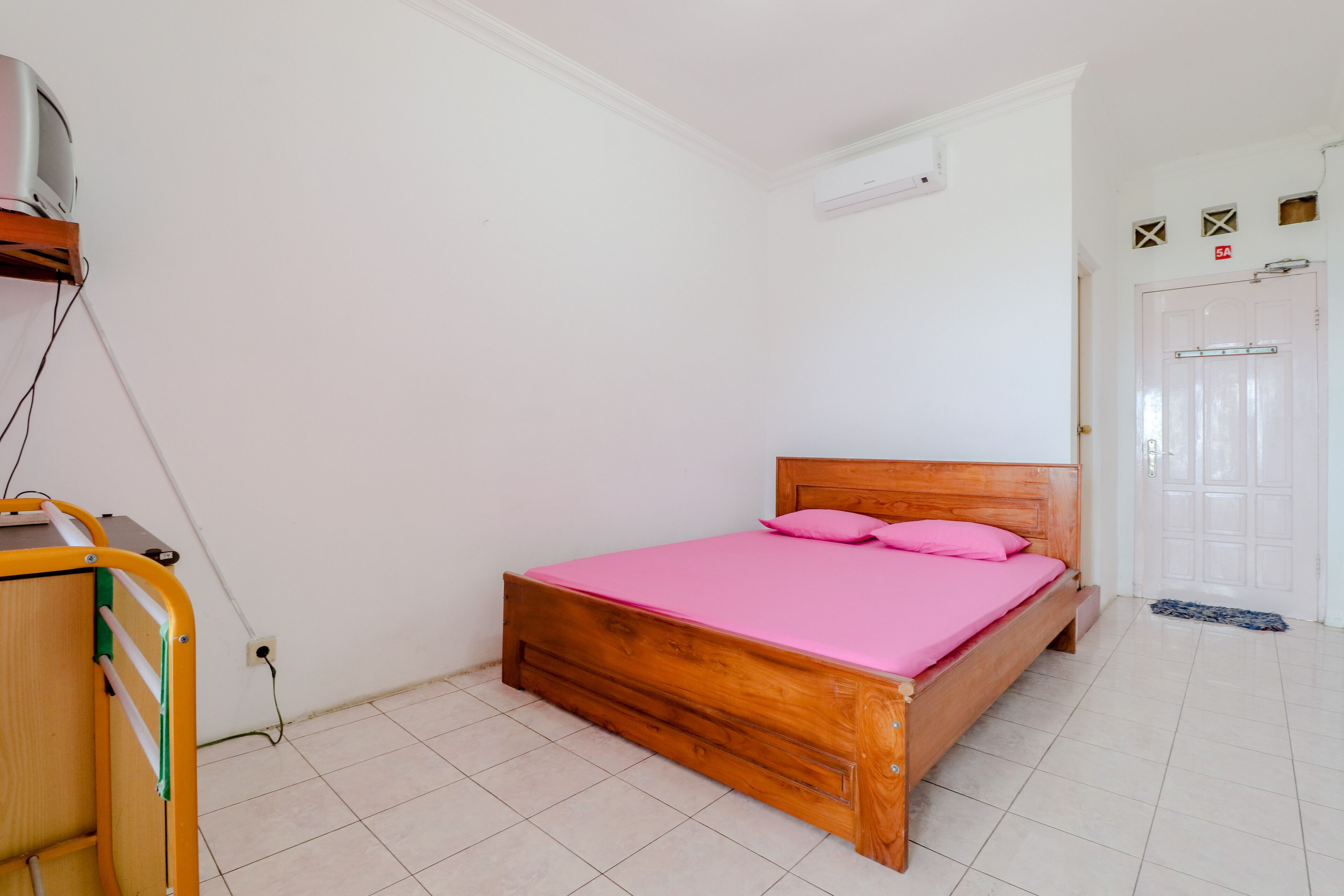 A bedroom with a wooden bed, a pink mattress, and a wooden headboard.