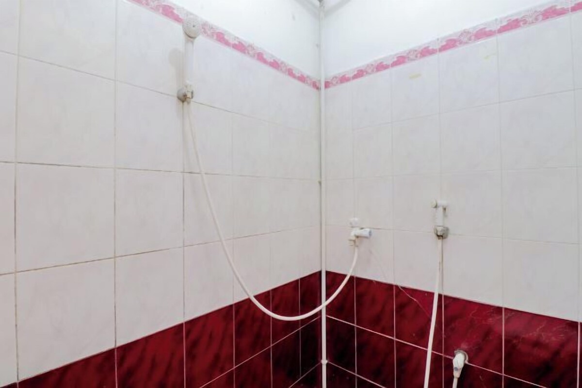 A bathroom with white and red tiles, a shower area, and a corner sink.