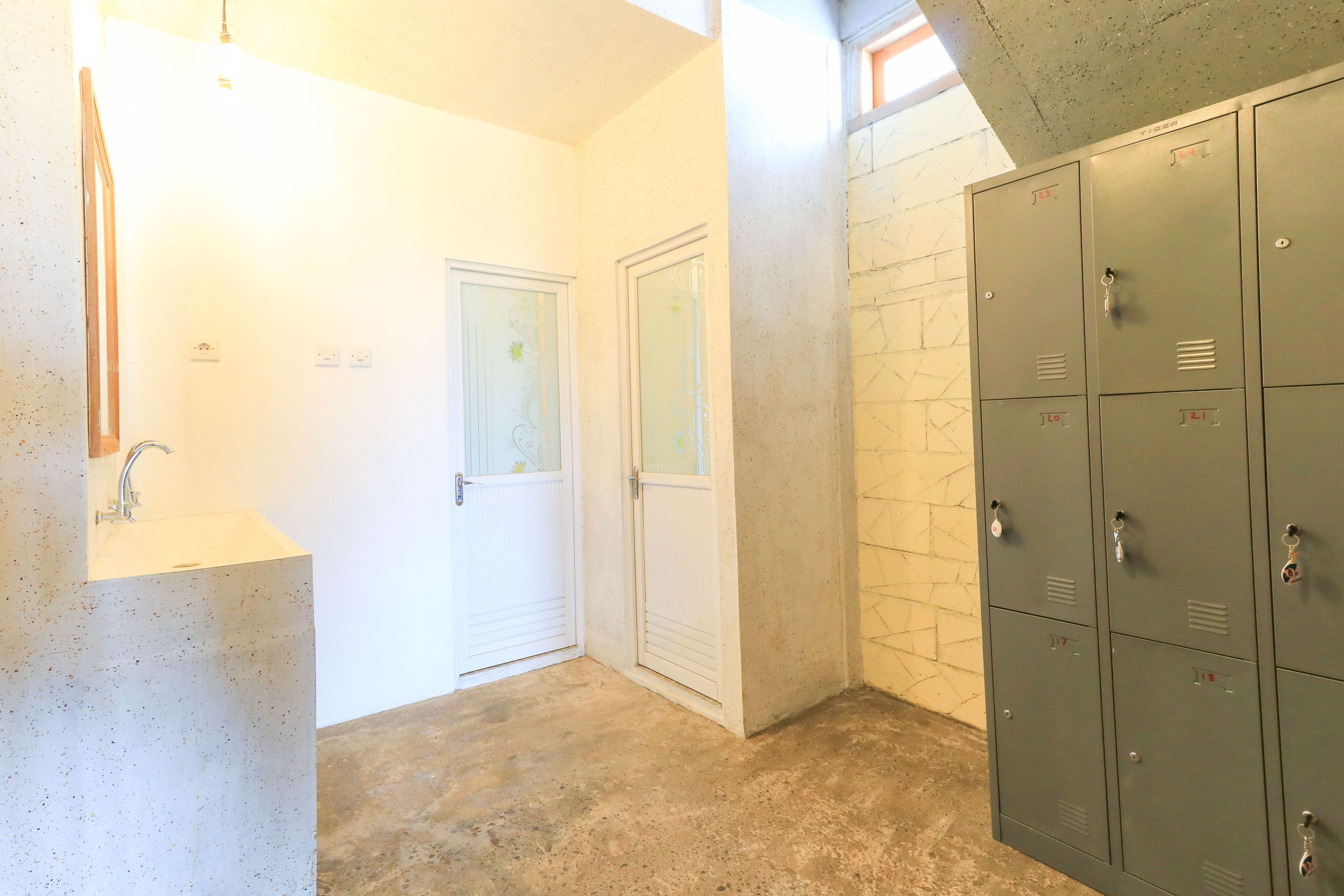 A bathroom with a sink, two doors, and a set of lockers.