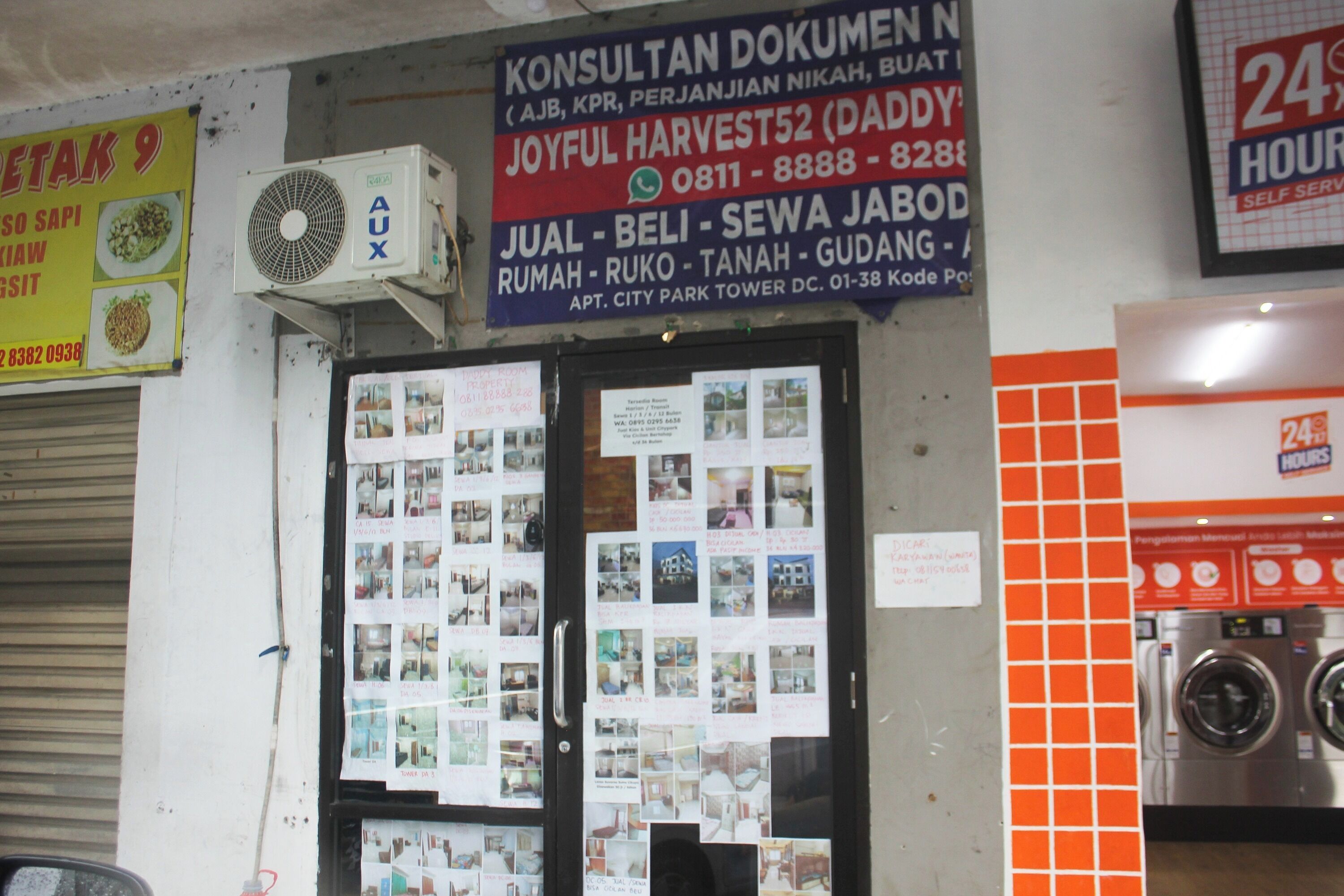 Un establecimiento con un cartel que anuncia servicio las 24 horas, un tablón de anuncios con diversas imágenes y una lavadora a la vista en el interior.