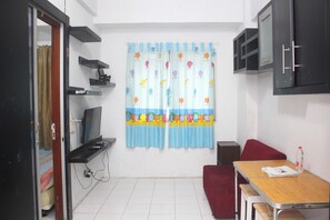 Um quarto pequeno com uma escrivaninha, uma cadeira vermelha, uma televisão e um guarda-roupa.