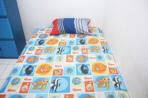 Uma cama com um cobre-leito temático do Nemo, um travesseiro listrado e uma parede azul.