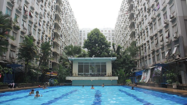 A swimming pool surrounded by high-rise residential buildings. - Daddy's Room Apartemen City Park (Jakarta)