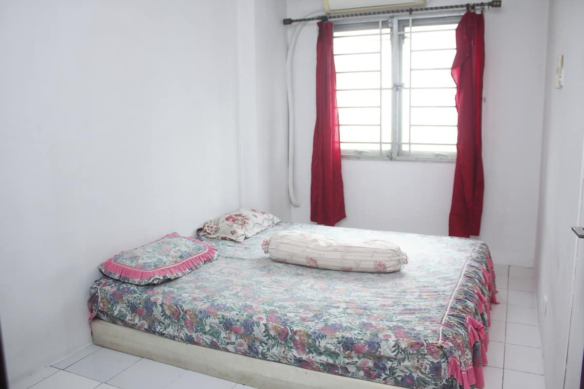 Ein Schlafzimmer mit einem Bett, roten Vorhängen und einem Fenster.