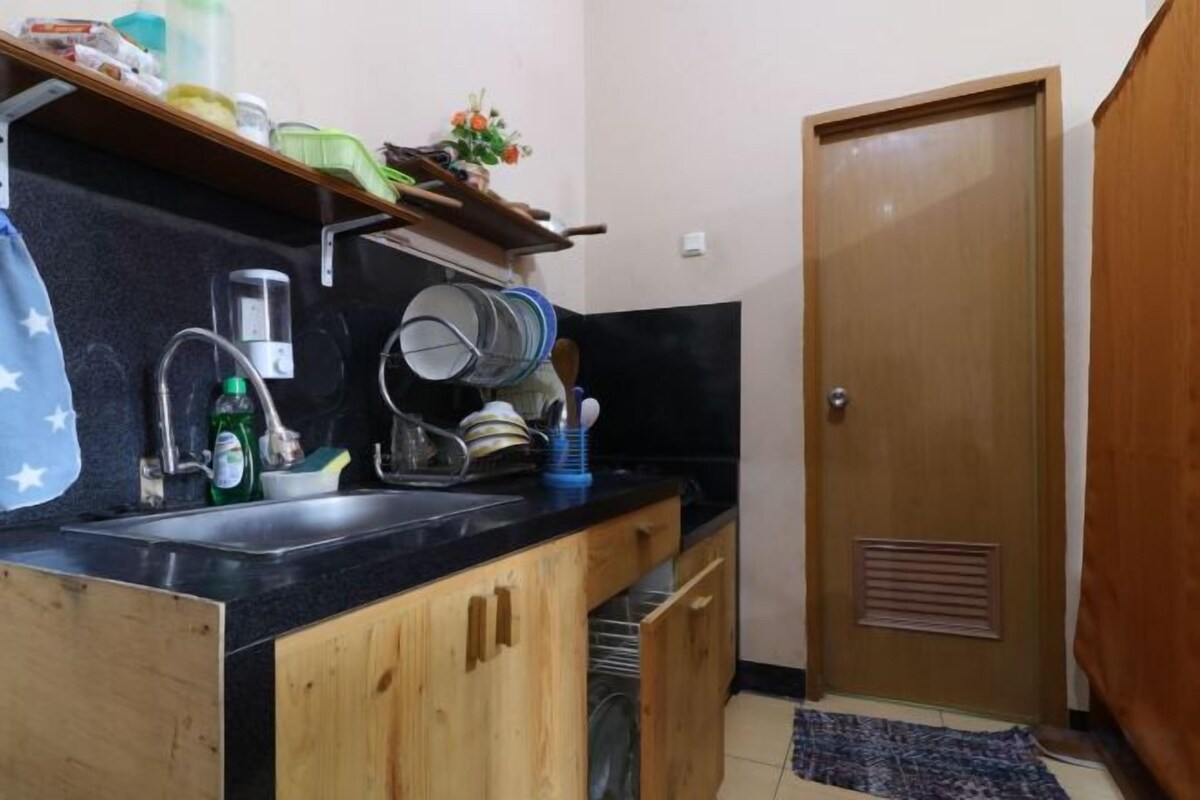 A compact kitchen with a sink, cabinets, and a door.