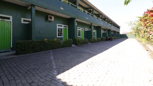 Un edificio con facciata verde, numerose finestre e un vialetto lastricato.