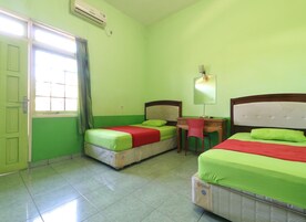 A room with two beds, a desk, a chair, and an air conditioning unit.