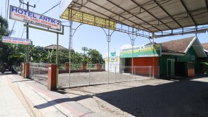 Ingresso di un hotel con cancello in metallo, area d'attesa coperta e cartelli che pubblicizzano uno sconto del 10% sulle prenotazioni delle camere.