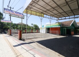 A hotel entrance with a metal gate, a covered waiting area, and signs advertising a 10% discount for room bookings.