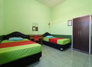 A room with two beds, a desk, a chair, a wardrobe, and a mirror.