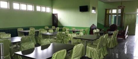 A conference room with green walls, multiple tables, and chairs.