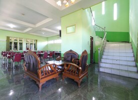 A spacious room with green walls, a staircase, and multiple tables and chairs.