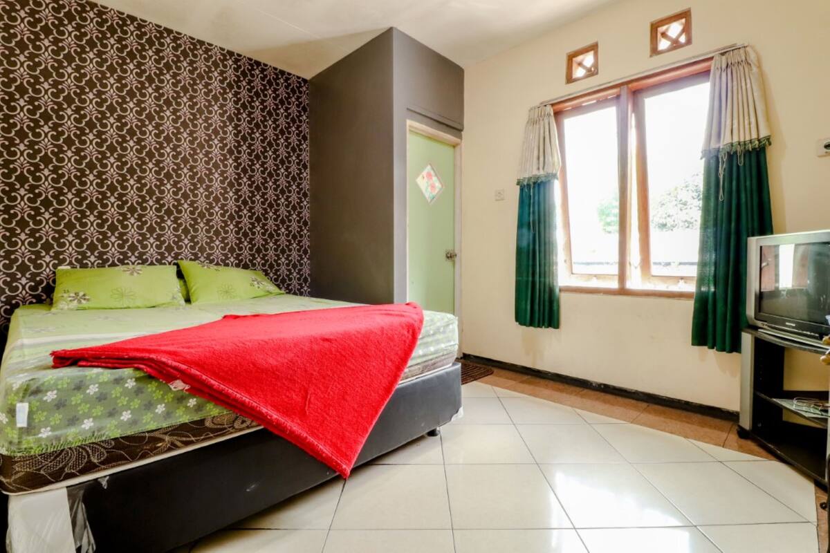 A room with a bed, a television, and a window with curtains.