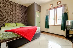 A room with a bed, a television, and a window with curtains.