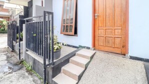 A house with a wooden door, a window with a decorative frame, and a black metal gate. - Puspa Sari Villa and Homestay (Batu)