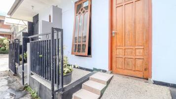 Una casa con puerta de madera, ventana con marco decorativo y portón de metal negro.