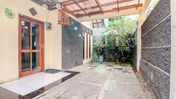 A corridor with a tiled floor, a wooden door, and a stone wall. - Puspa Sari Villa and Homestay (Batu)