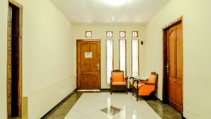 A hallway with a wooden door, a chair, and a table. - Puspa Sari Villa and Homestay (Batu)