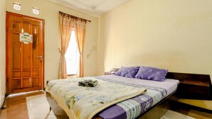 A bedroom with a bed, a wooden door, and a window with curtains. - Puspa Sari Villa and Homestay (Batu)