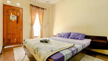 Un dormitorio con una cama, una puerta de madera y un ventanal con cortinas.
